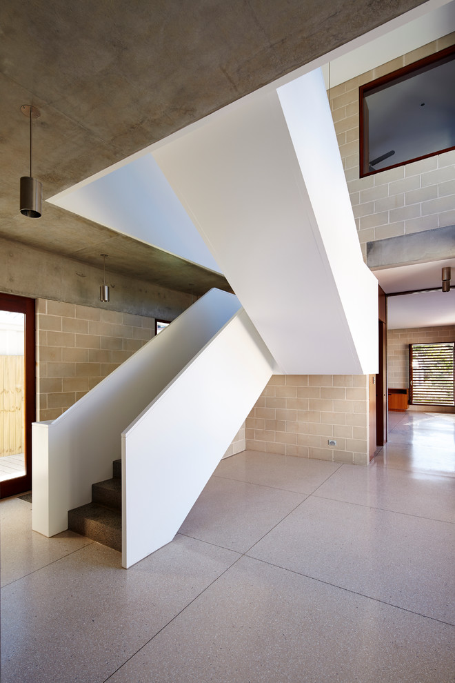 シドニーにあるコンテンポラリースタイルのおしゃれな折り返し階段 (コンクリートの蹴込み板、木材の手すり) の写真