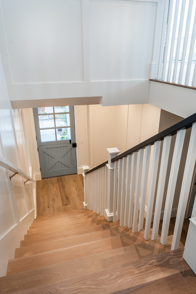 Ejemplo de escalera en L de estilo de casa de campo con escalones de madera, contrahuellas de madera pintada y barandilla de madera