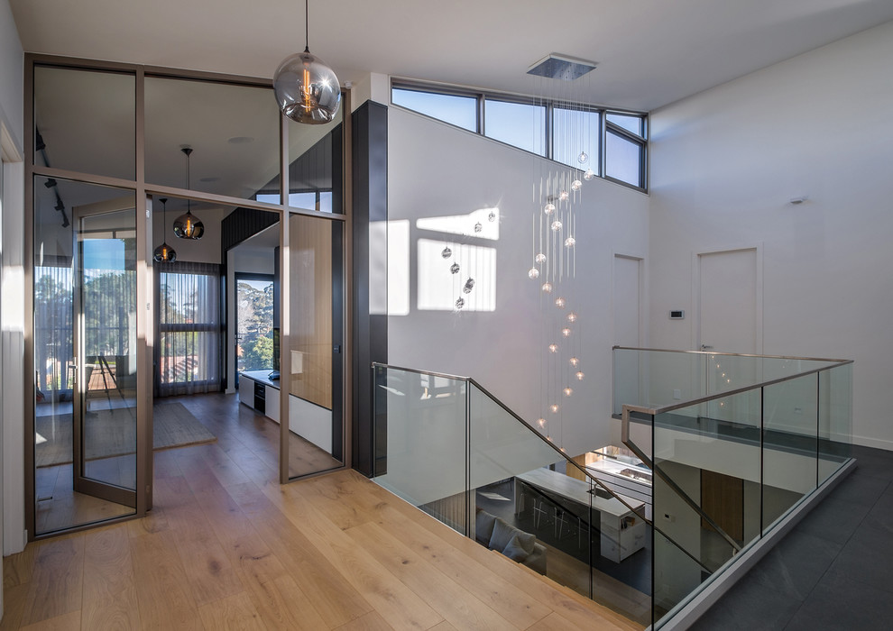 Ejemplo de escalera recta minimalista de tamaño medio sin contrahuella con escalones de madera y barandilla de vidrio