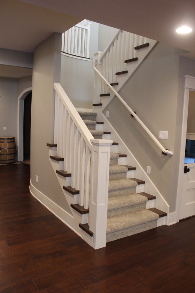 Cette photo montre un grand escalier chic en L avec des marches en moquette et des contremarches en bois.
