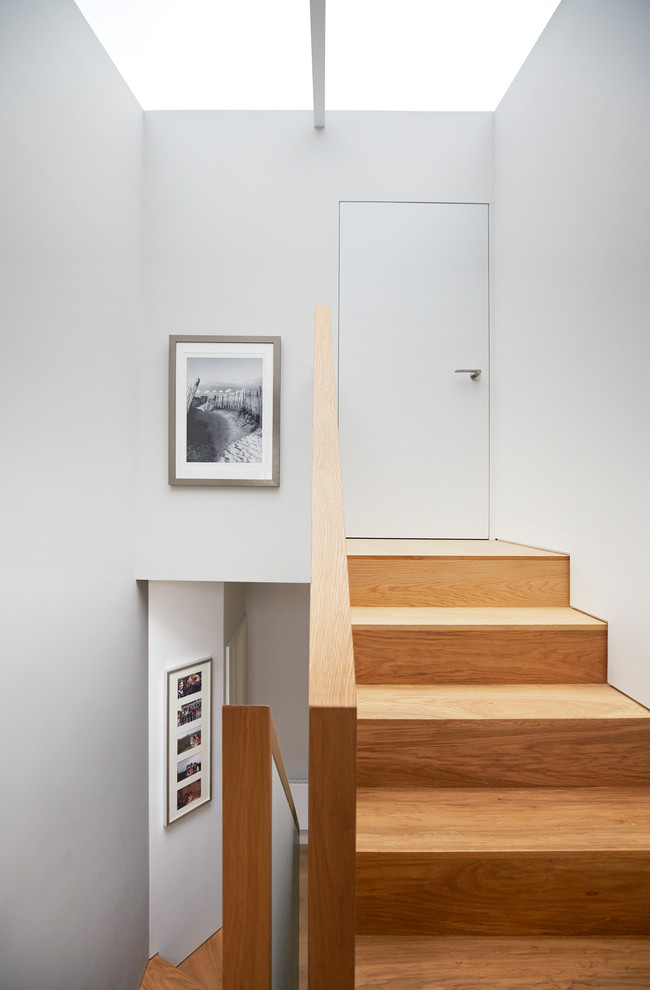 Foto de escalera en U contemporánea de tamaño medio con escalones de madera, contrahuellas de madera y barandilla de vidrio