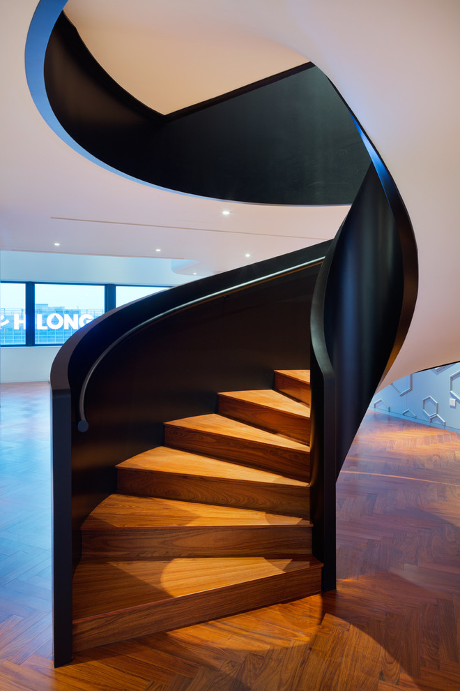 Large contemporary wood spiral staircase in Other with wood risers.