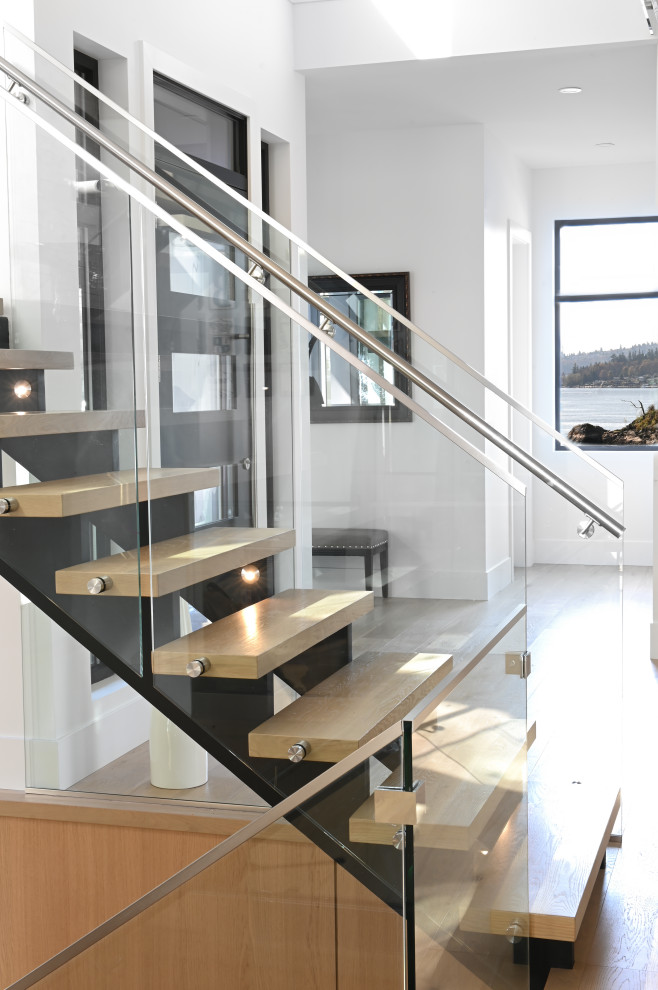 Aménagement d'un escalier sans contremarche contemporain avec des marches en bois et un garde-corps en verre.
