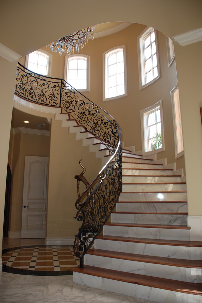 Стильный дизайн: изогнутая лестница среднего размера в средиземноморском стиле с деревянными ступенями, подступенками из мрамора и металлическими перилами - последний тренд