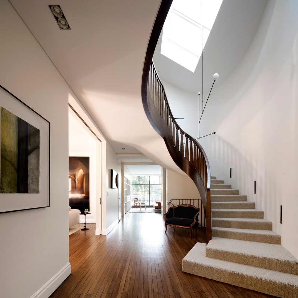 Свежая идея для дизайна: большая изогнутая лестница в стиле неоклассика (современная классика) с ступенями с ковровым покрытием и ковровыми подступенками - отличное фото интерьера