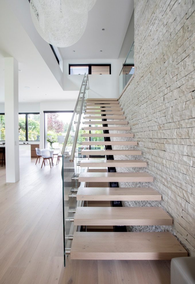 Diseño de escalera suspendida actual de tamaño medio con escalones de madera, barandilla de metal y ladrillo