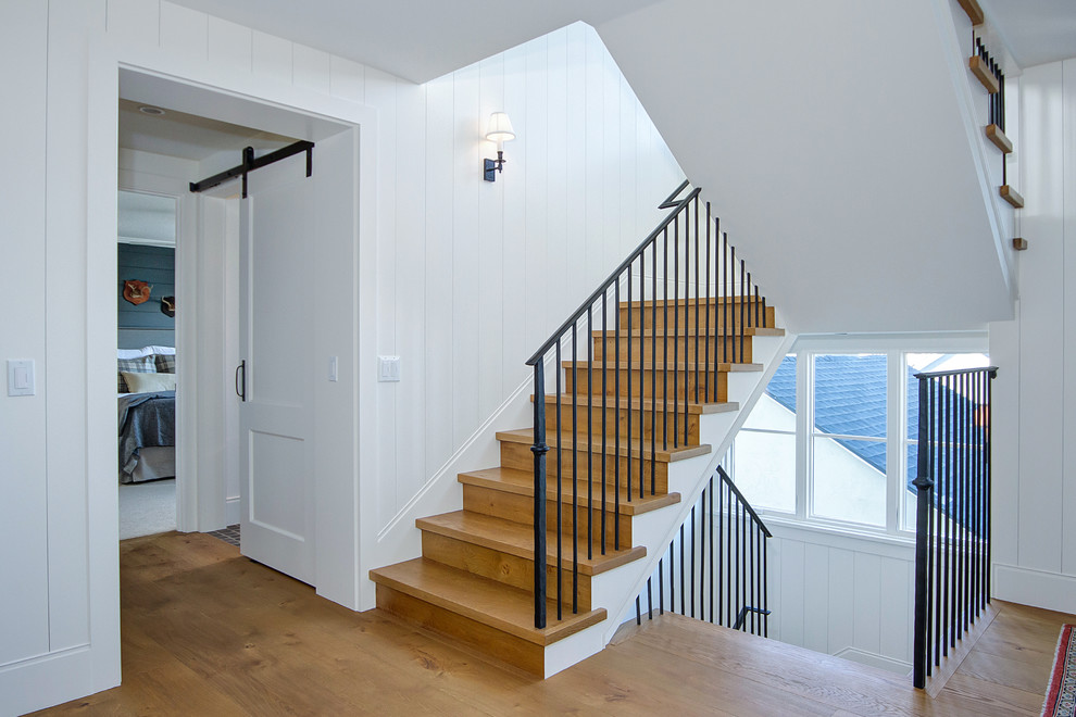 Ejemplo de escalera en U de estilo de casa de campo grande con escalones de madera, contrahuellas de madera y barandilla de metal