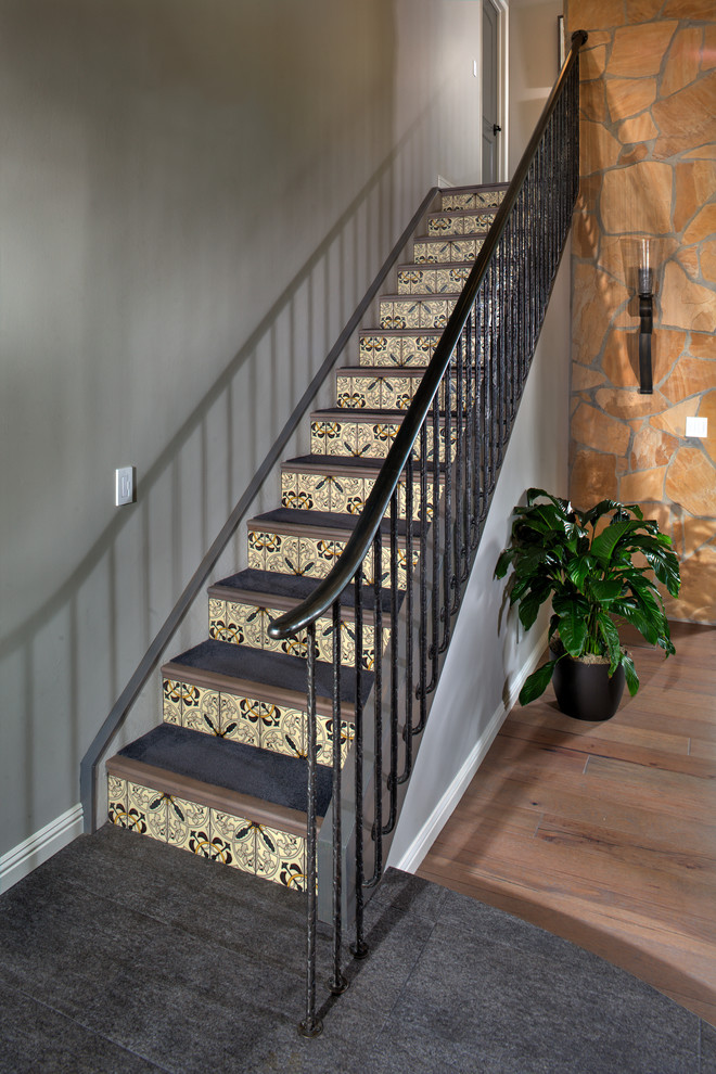 Diseño de escalera minimalista con escalones enmoquetados, contrahuellas con baldosas y/o azulejos y barandilla de metal