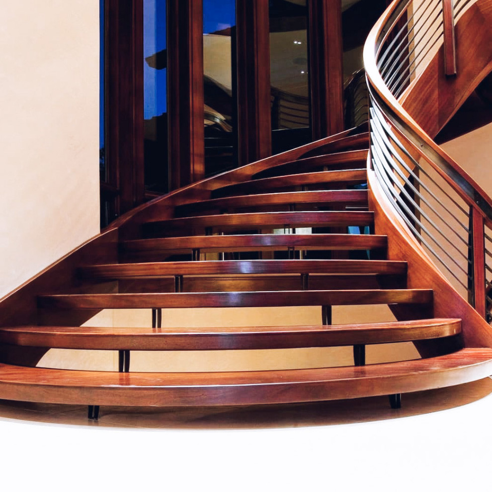 Стильный дизайн: большая изогнутая лестница с деревянными ступенями и перилами из смешанных материалов без подступенок - последний тренд