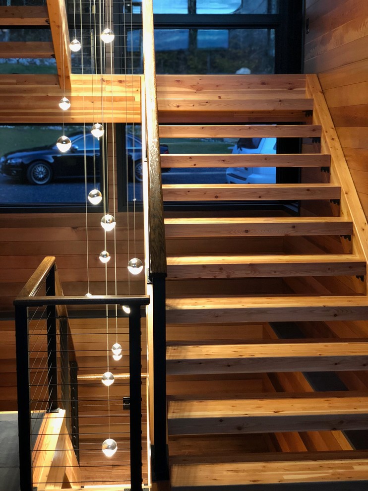 Diseño de escalera en U rústica grande sin contrahuella con escalones de madera y barandilla de cable