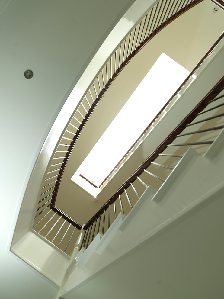 Стильный дизайн: большая изогнутая лестница в классическом стиле с крашенными деревянными ступенями и крашенными деревянными подступенками - последний тренд
