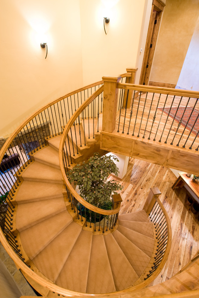 На фото: большая изогнутая деревянная лестница в классическом стиле с металлическими ступенями с