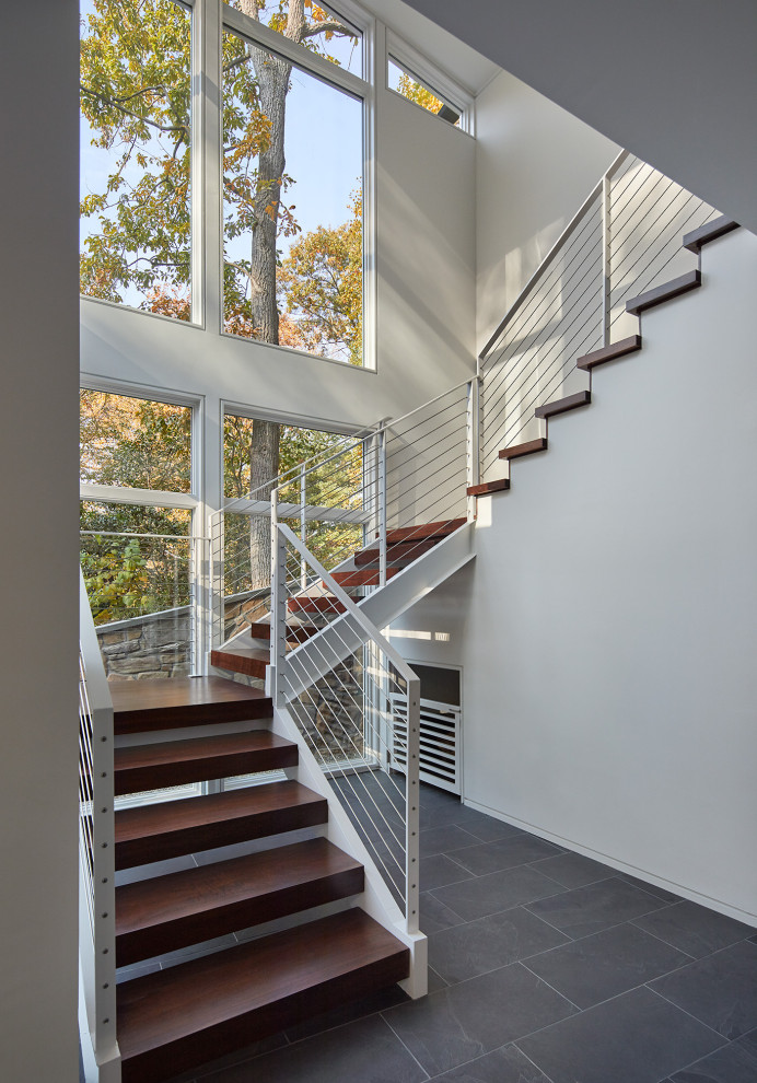 На фото: п-образная лестница в современном стиле с деревянными ступенями и металлическими перилами с