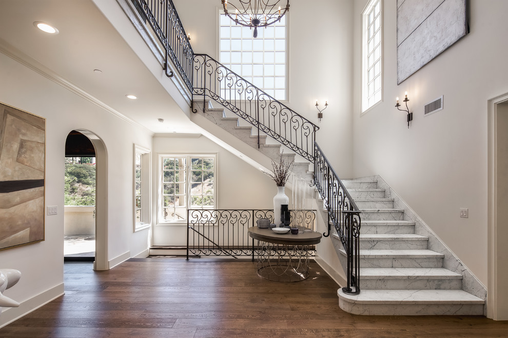 Example of a tuscan marble l-shaped metal railing staircase design in Los Angeles with marble risers