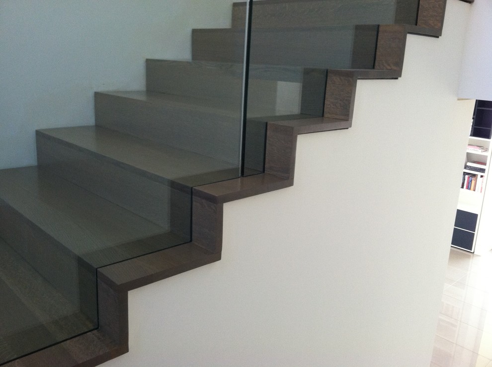 Imagen de escalera en U contemporánea de tamaño medio con escalones de madera, contrahuellas de madera y barandilla de vidrio
