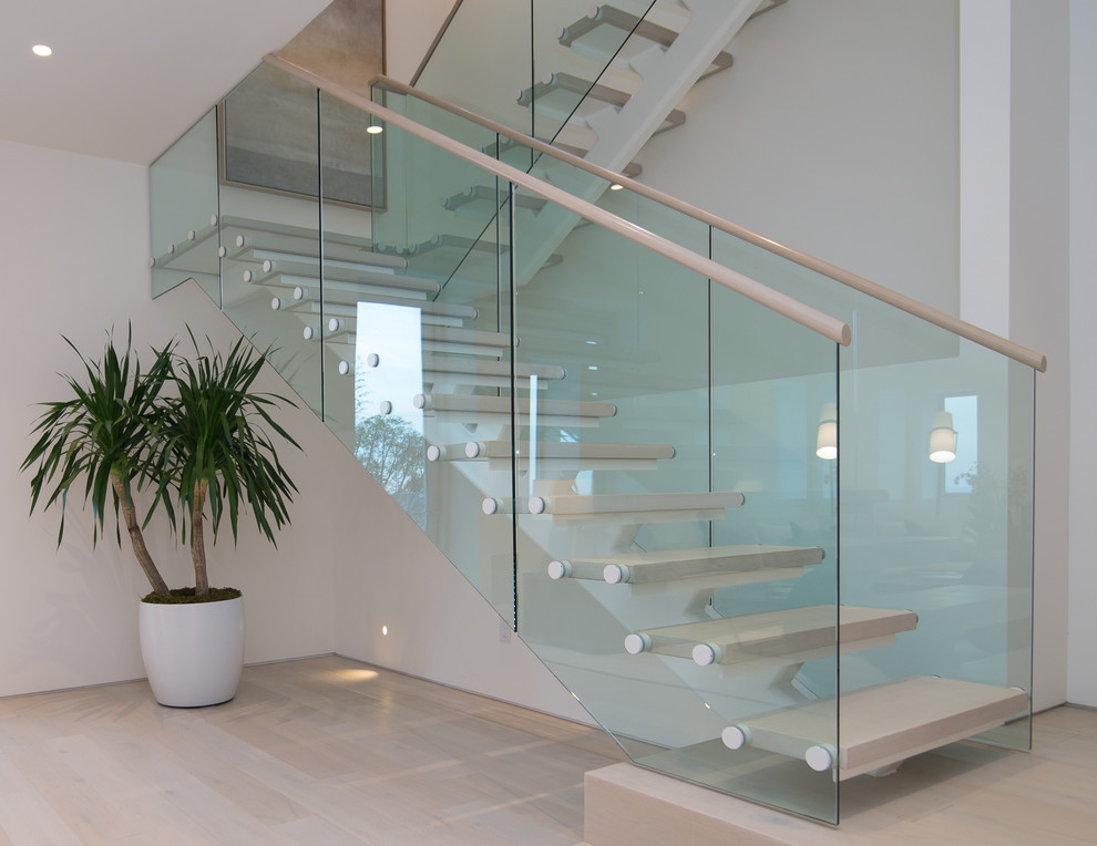 На фото: лестница на больцах, среднего размера в современном стиле с деревянными ступенями и стеклянными перилами без подступенок с
