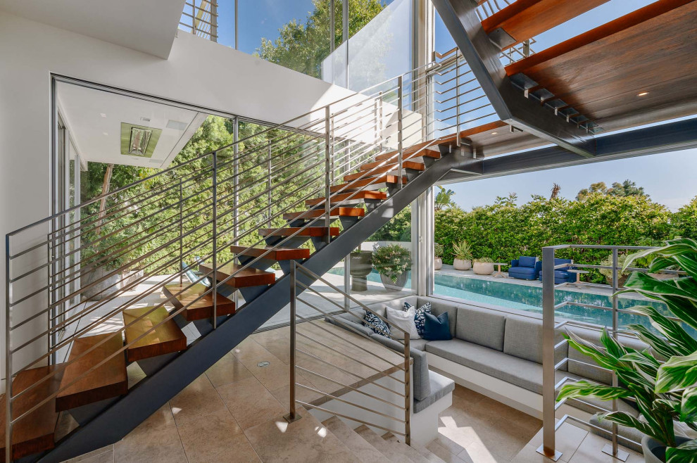 Photo of an expansive contemporary wood u-shaped metal railing staircase in Los Angeles with open risers.