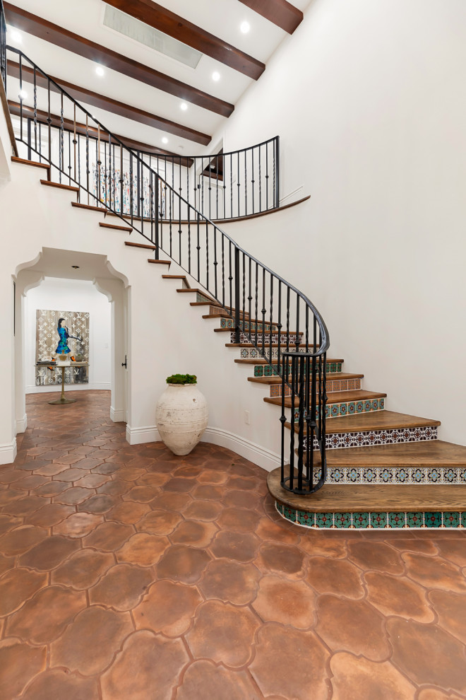 Inspiration for a mediterranean curved metal railing staircase in Los Angeles with tiled risers.