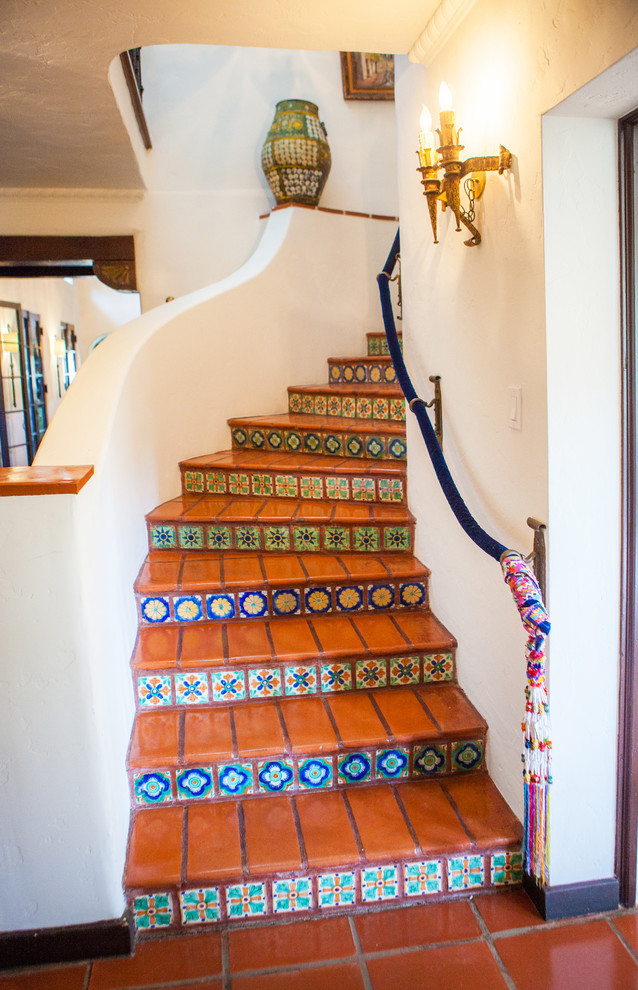 Réalisation d'un escalier courbe méditerranéen avec des contremarches carrelées et des marches en terre cuite.