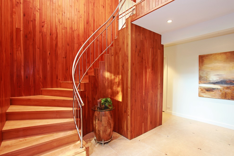 Modelo de escalera curva actual de tamaño medio con escalones de madera, contrahuellas de madera y barandilla de metal