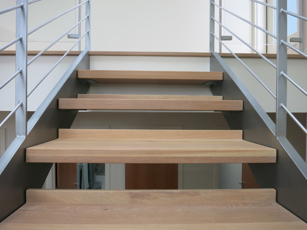 This is an example of a large contemporary wood u-shaped staircase in Seattle with open risers.