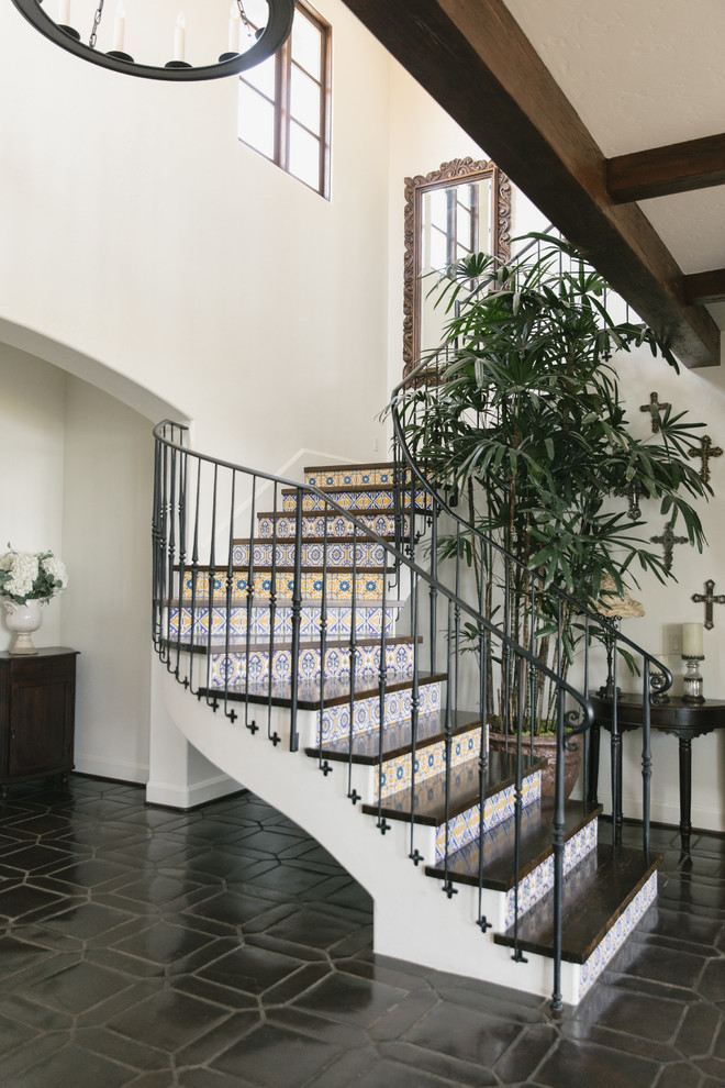 This is an example of a mediterranean wood curved metal railing staircase in Los Angeles with tiled risers.
