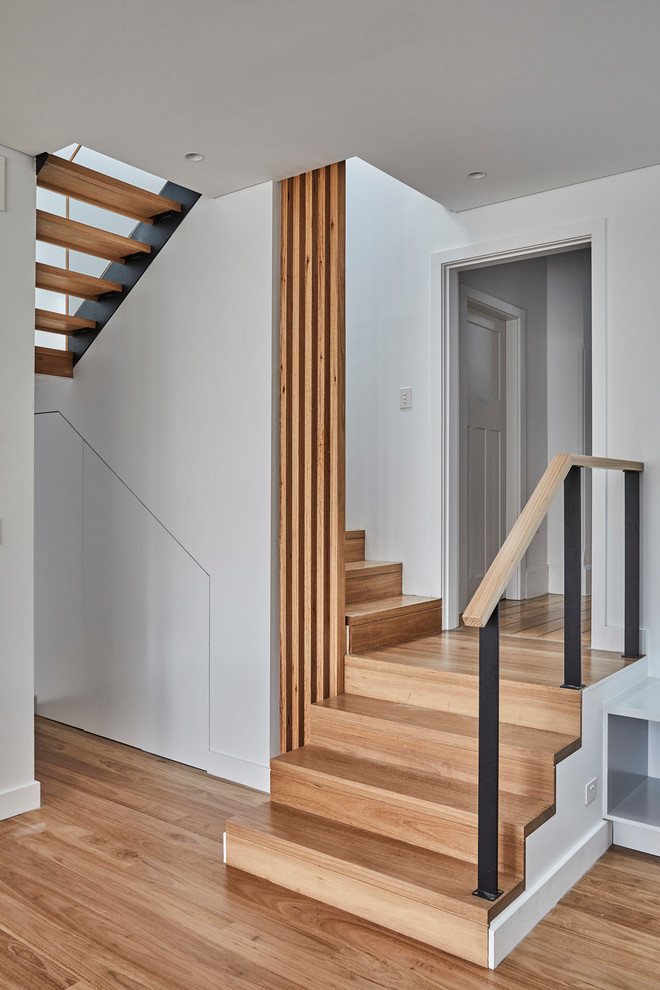 Ejemplo de escalera curva moderna de tamaño medio con escalones de madera, contrahuellas de madera y barandilla de metal