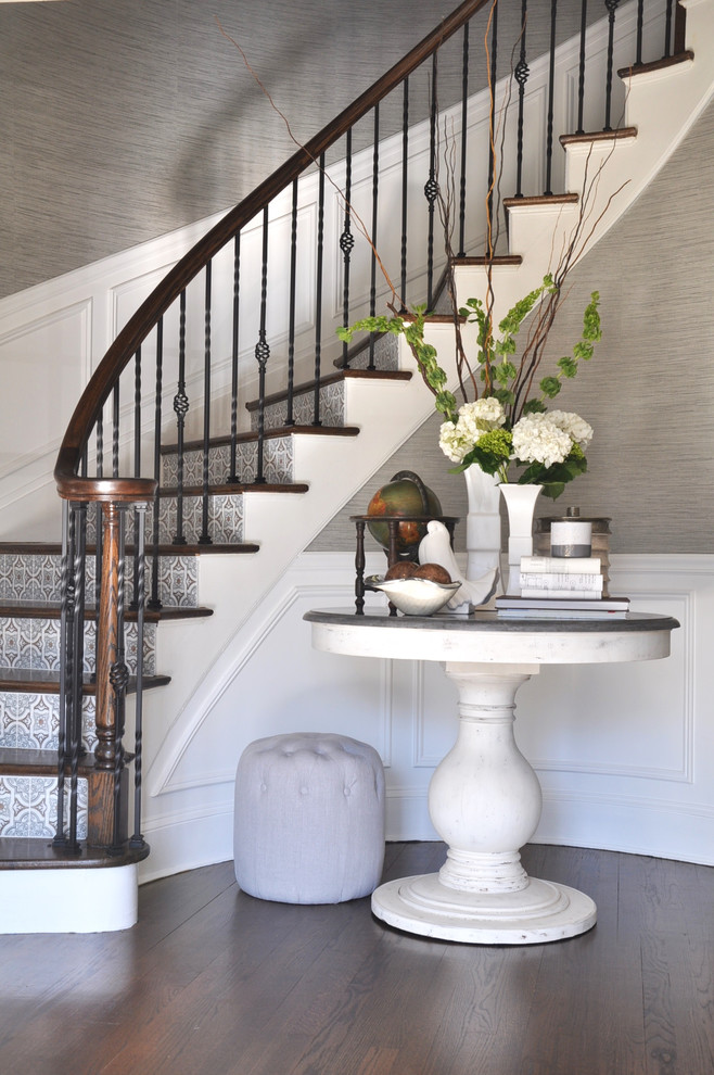 Diseño de escalera curva clásica con escalones de madera, contrahuellas con baldosas y/o azulejos y barandilla de varios materiales