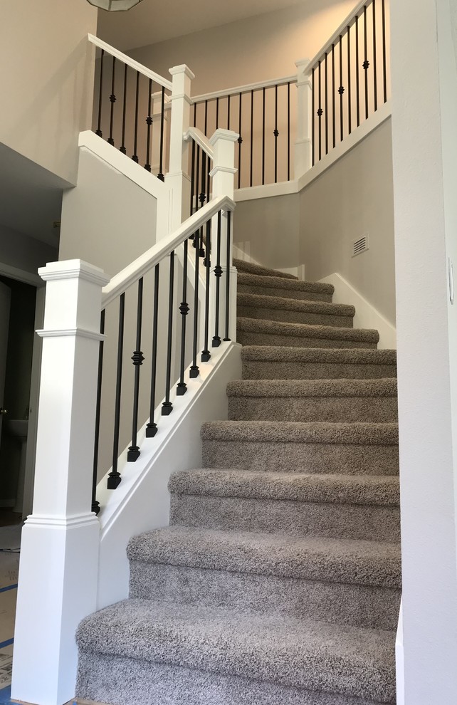 Пример оригинального дизайна: изогнутая лестница среднего размера в стиле кантри с ступенями с ковровым покрытием, ковровыми подступенками и деревянными перилами