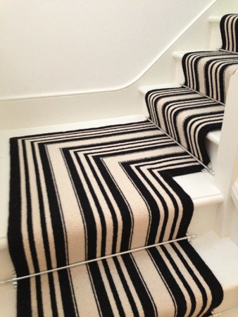 This is an example of a medium sized contemporary carpeted u-shaped wood railing staircase in London with carpeted risers.