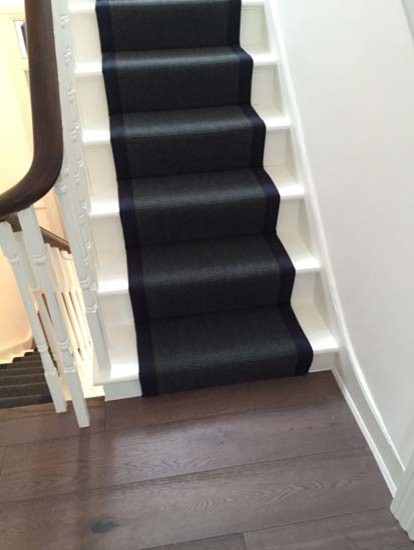 Traditional carpeted u-shaped wood railing staircase in London with carpeted risers.