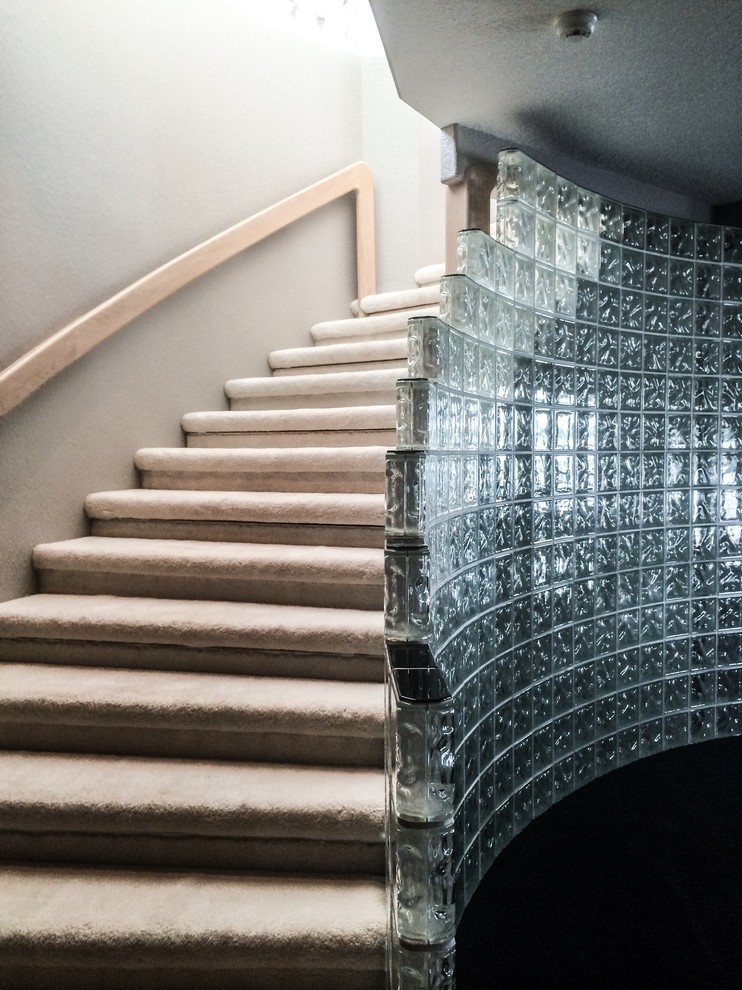На фото: большая изогнутая лестница в стиле ретро с ступенями с ковровым покрытием и ковровыми подступенками с