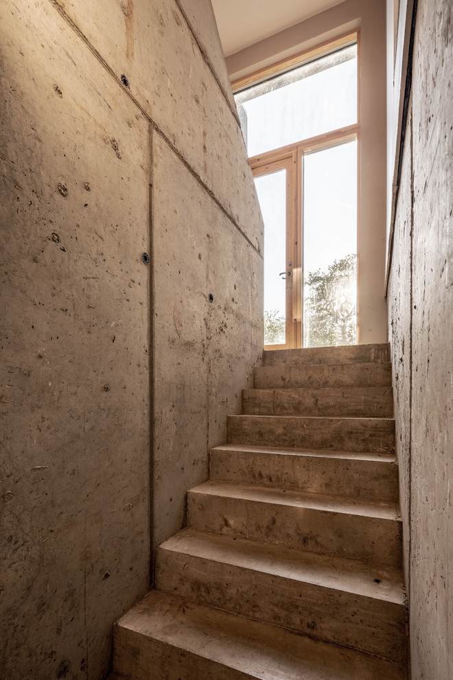 Imagen de escalera en U minimalista con escalones de hormigón y contrahuellas de hormigón