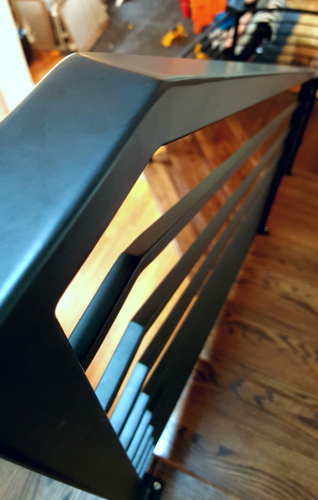 Foto di una grande scala curva scandinava con parapetto in metallo, pedata in legno e alzata in legno