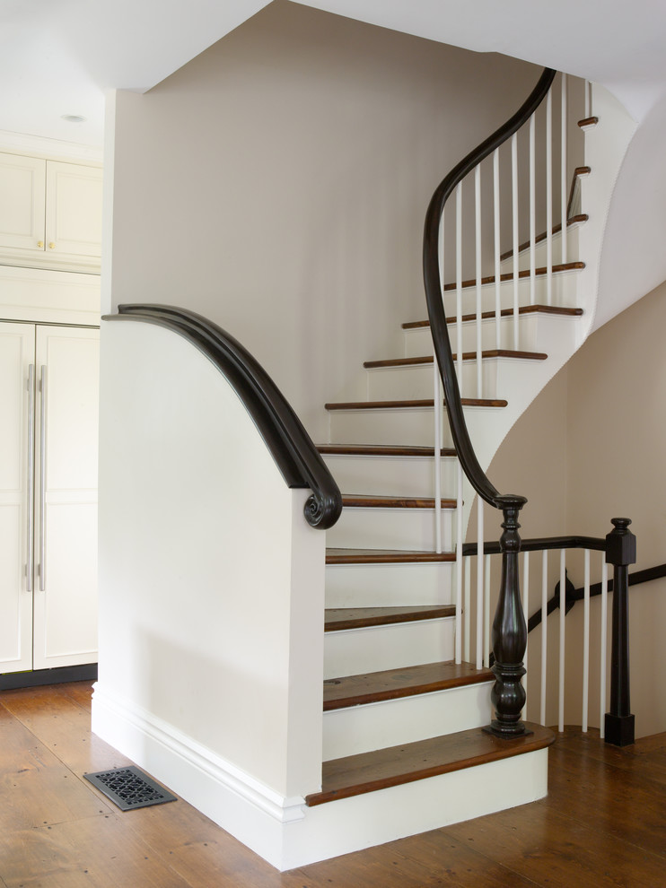 This is an example of a traditional wood curved staircase in Boston with painted wood risers.