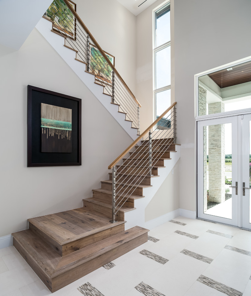 Стильный дизайн: большая п-образная деревянная лестница в стиле неоклассика (современная классика) с деревянными ступенями и перилами из тросов - последний тренд