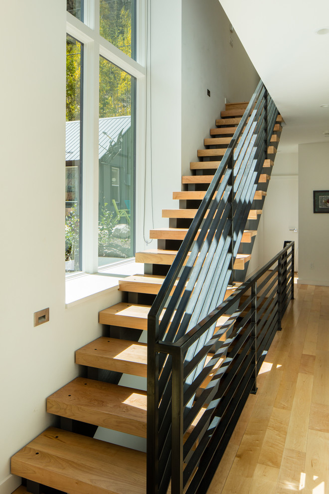 Diseño de escalera suspendida minimalista grande con contrahuellas de madera