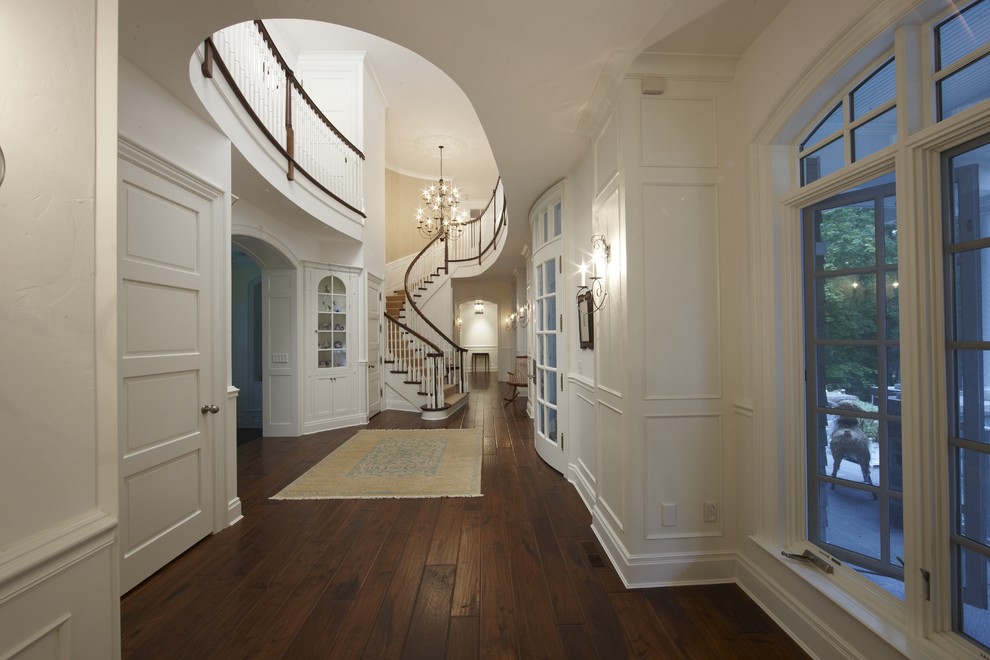 Aménagement d'un grand escalier peint courbe classique avec des marches en bois et un garde-corps en bois.