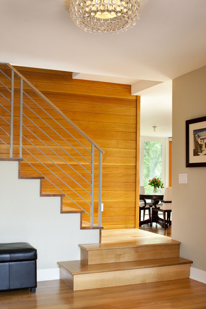 Cette photo montre un escalier moderne avec des marches en bois, des contremarches en bois et un garde-corps en métal.