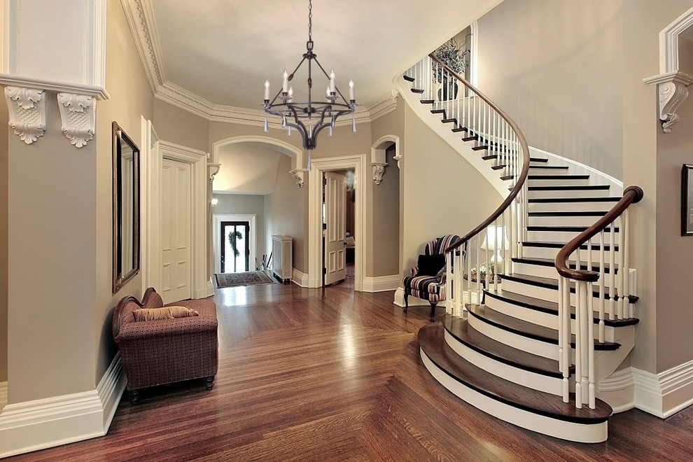 Стильный дизайн: изогнутая деревянная лестница среднего размера в стиле неоклассика (современная классика) с деревянными ступенями и деревянными перилами - последний тренд