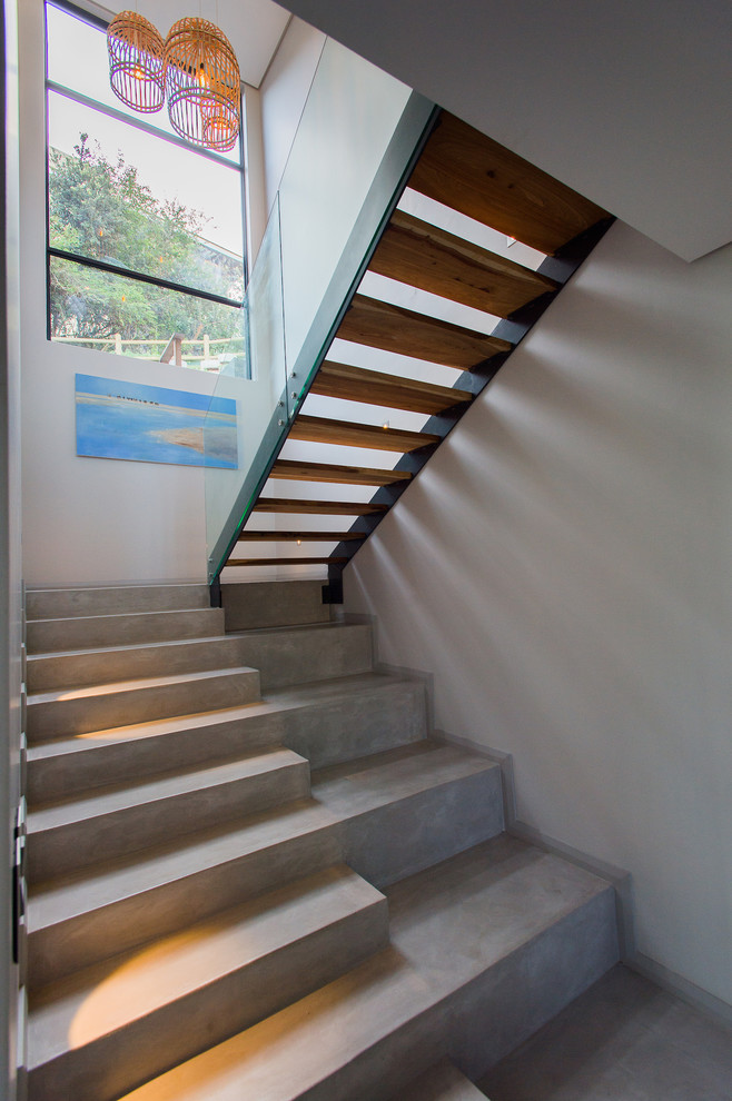 На фото: п-образная бетонная лестница в современном стиле с бетонными ступенями и стеклянными перилами с