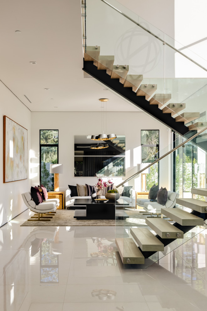 Стильный дизайн: огромная угловая деревянная лестница в современном стиле с металлическими ступенями и стеклянными перилами - последний тренд