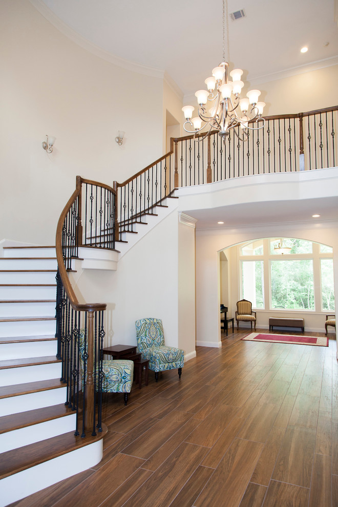 На фото: изогнутая лестница среднего размера в классическом стиле с деревянными ступенями и крашенными деревянными подступенками