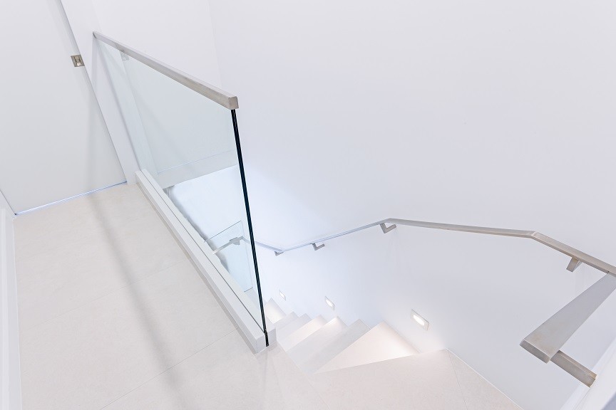 Cette image montre un petit escalier minimaliste en L avec un garde-corps en verre.