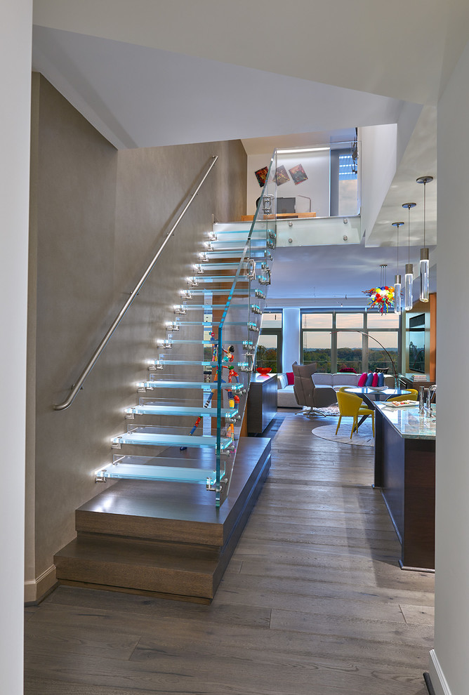 Idée de décoration pour un escalier sans contremarche droit design de taille moyenne avec un garde-corps en verre, des marches en verre et éclairage.