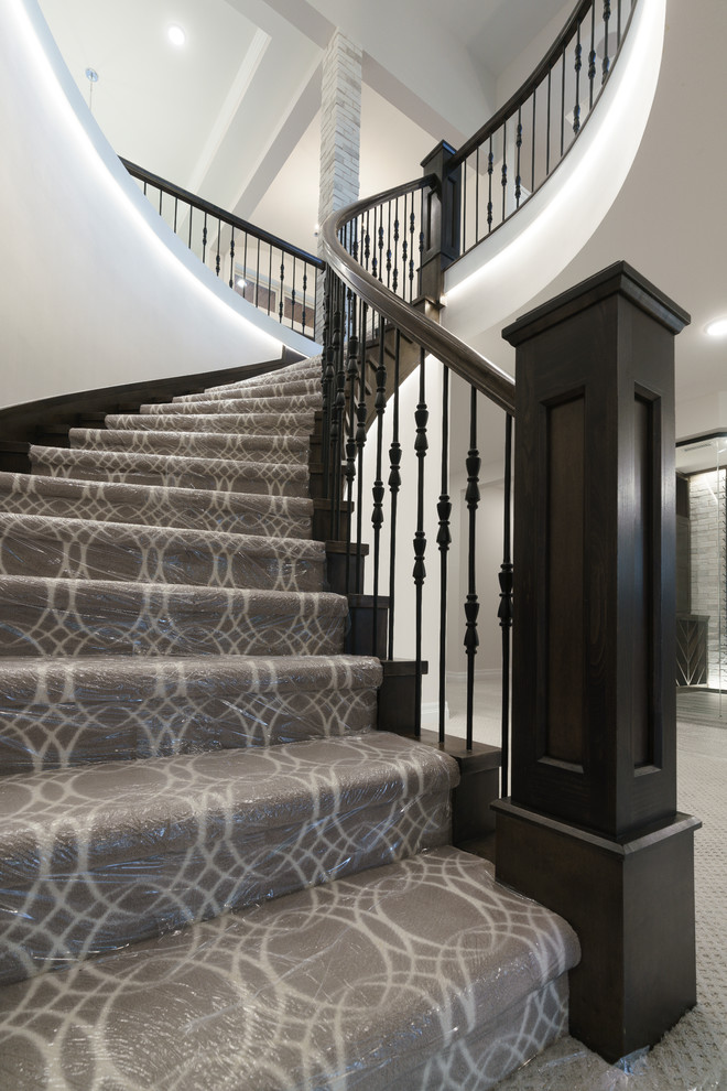 Свежая идея для дизайна: большая изогнутая лестница в стиле неоклассика (современная классика) с ступенями с ковровым покрытием, деревянными перилами и ковровыми подступенками - отличное фото интерьера