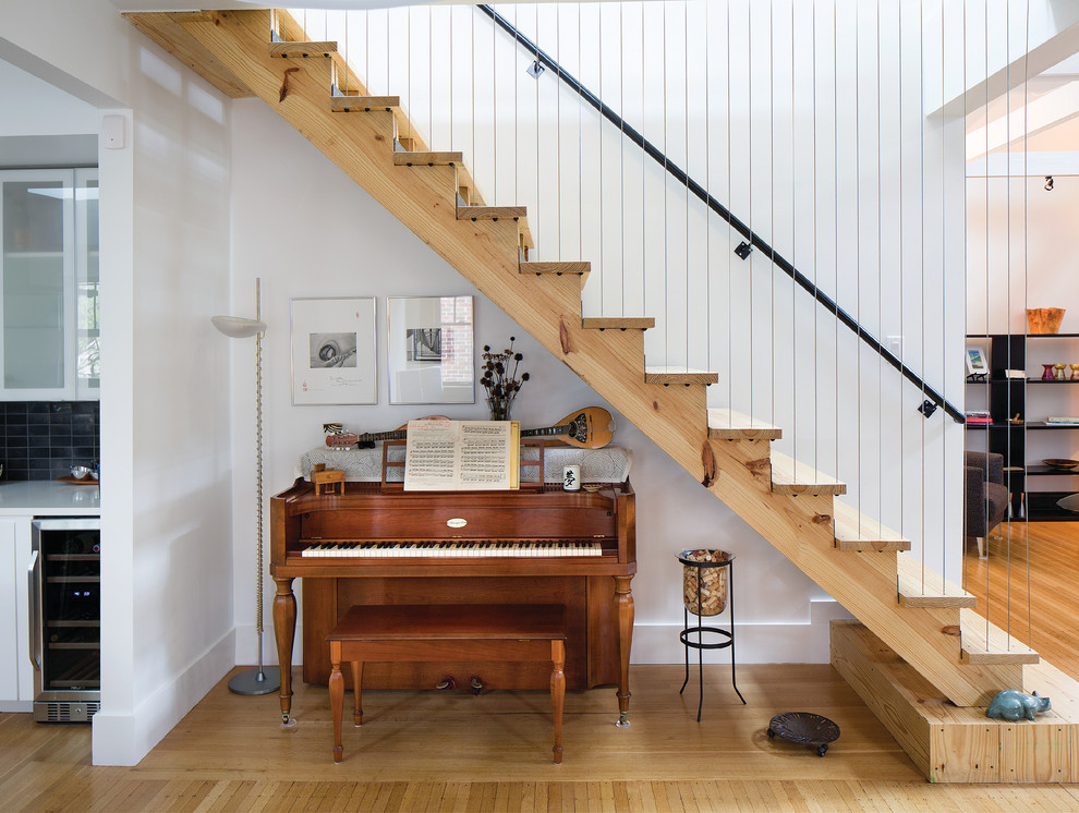 Cette image montre un escalier droit design de taille moyenne avec des marches en bois, des contremarches en bois, un garde-corps en câble et rangements.