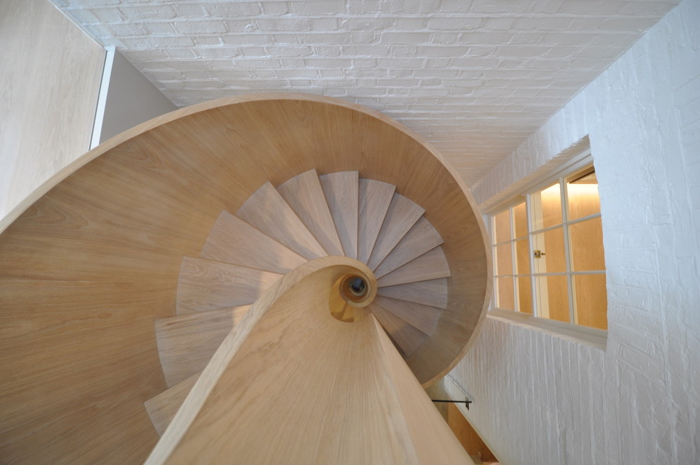 Modelo de escalera de caracol actual de tamaño medio con escalones de madera, contrahuellas de madera y barandilla de madera