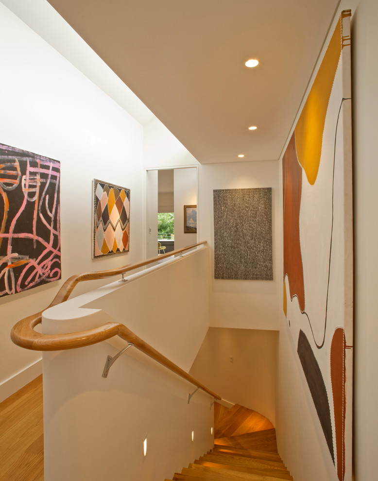 This is an example of a contemporary wood curved staircase in Sydney with wood risers.