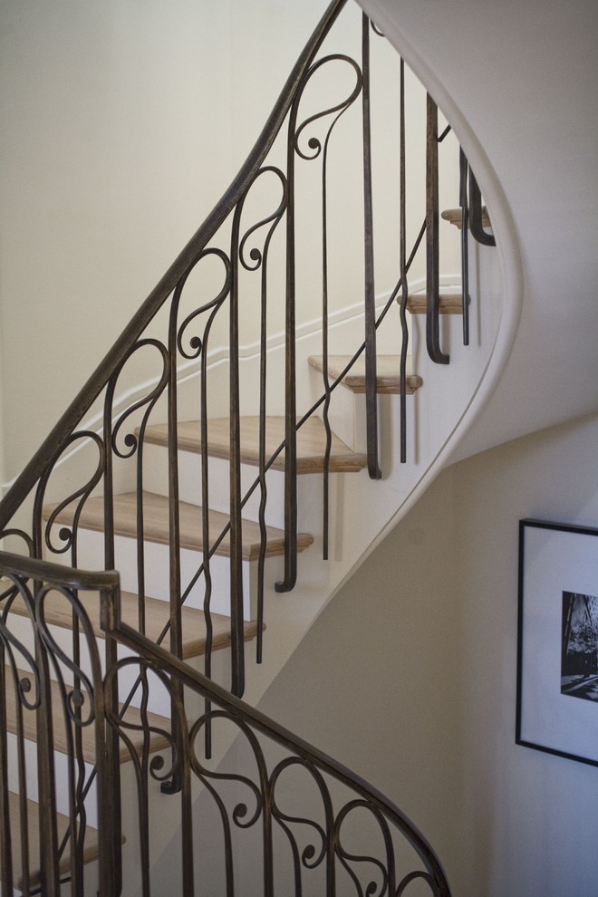 Ejemplo de escalera curva tradicional pequeña con escalones de madera y contrahuellas de madera